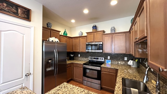 kitchen featuring hardwood / wood-style flooring, sink, stainless steel appliances, and stone counters