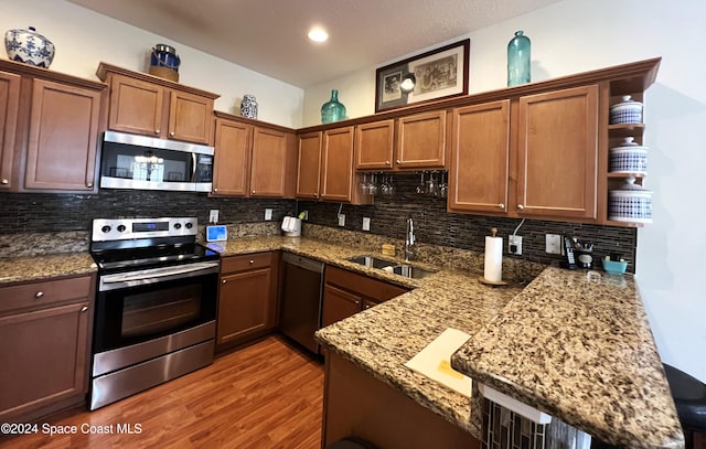 kitchen featuring wood-type flooring, sink, kitchen peninsula, and stainless steel appliances