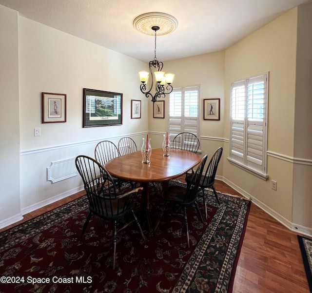 dining space with dark wood-type flooring and a chandelier