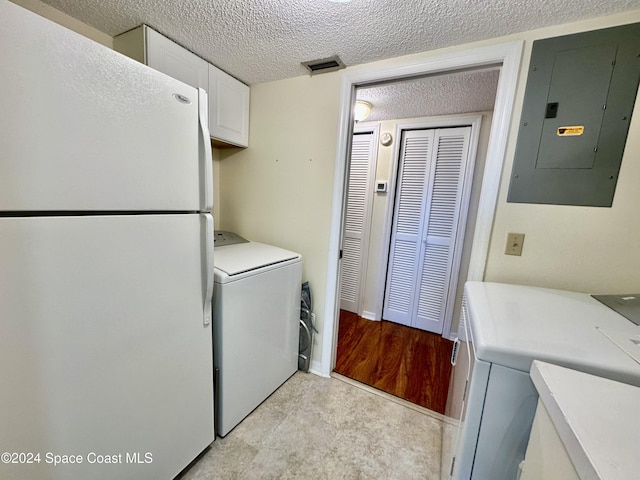 laundry room with electric panel, cabinets, a textured ceiling, and washer / clothes dryer