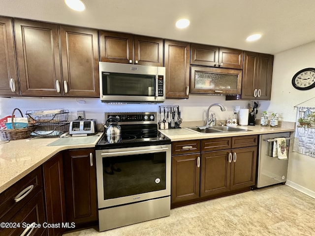 kitchen with appliances with stainless steel finishes, dark brown cabinets, and sink