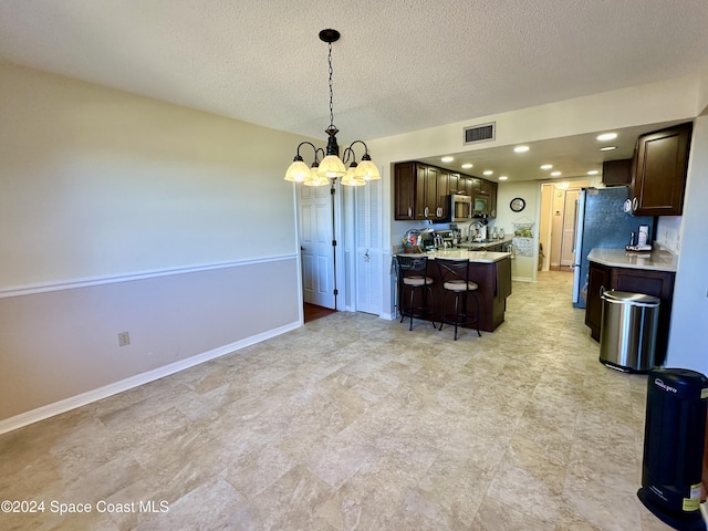 kitchen with a kitchen breakfast bar, stainless steel appliances, a chandelier, a kitchen island, and hanging light fixtures