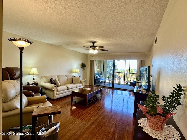 living room with ceiling fan, dark wood-type flooring, and a textured ceiling