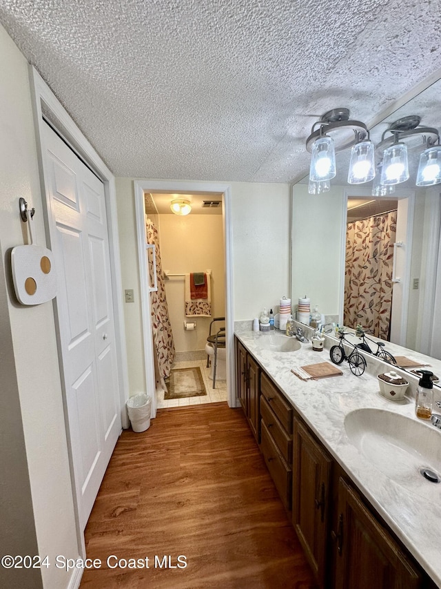 bathroom with a shower with curtain, hardwood / wood-style floors, vanity, and a textured ceiling