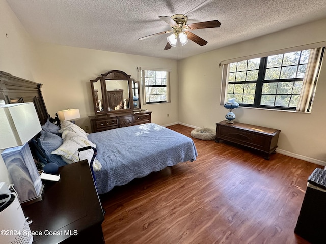 bedroom featuring dark hardwood / wood-style floors, ceiling fan, and a textured ceiling