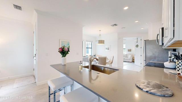 kitchen featuring sink, a kitchen breakfast bar, kitchen peninsula, pendant lighting, and white cabinets