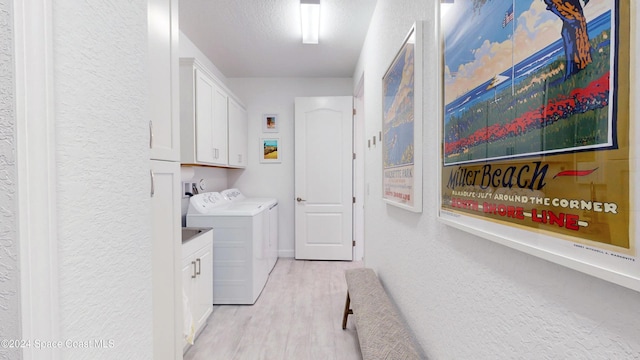 washroom with cabinets, a textured ceiling, washing machine and dryer, and light hardwood / wood-style flooring