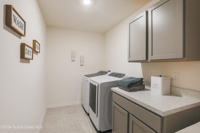 laundry room featuring washing machine and clothes dryer, light tile patterned floors, and cabinets