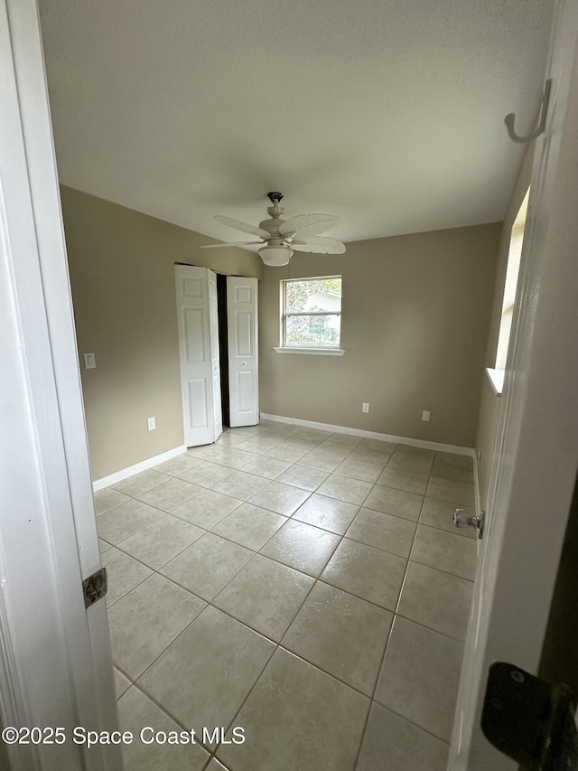 tiled spare room featuring ceiling fan