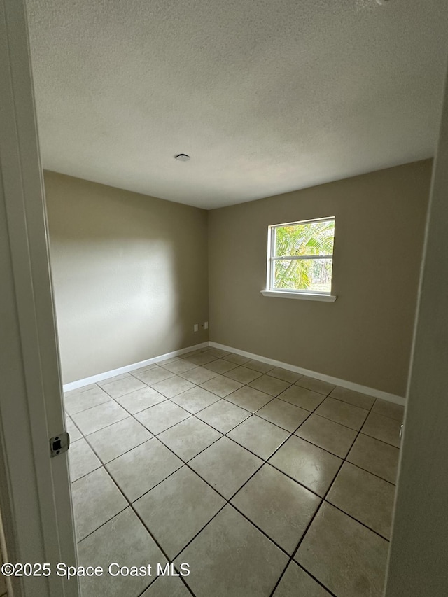 tiled empty room with a textured ceiling