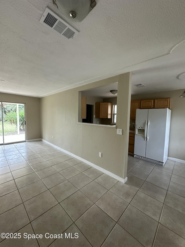 spare room with a textured ceiling and light tile patterned flooring