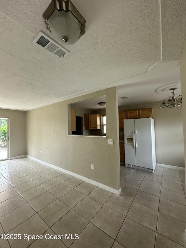 empty room with a textured ceiling and light tile patterned flooring