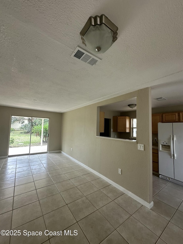 tiled spare room with a textured ceiling