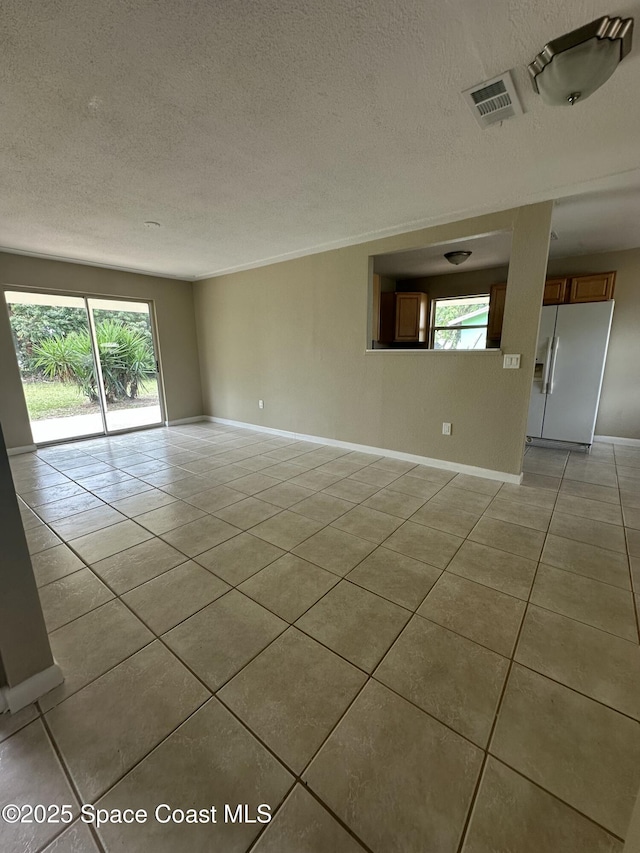 tiled empty room featuring a textured ceiling