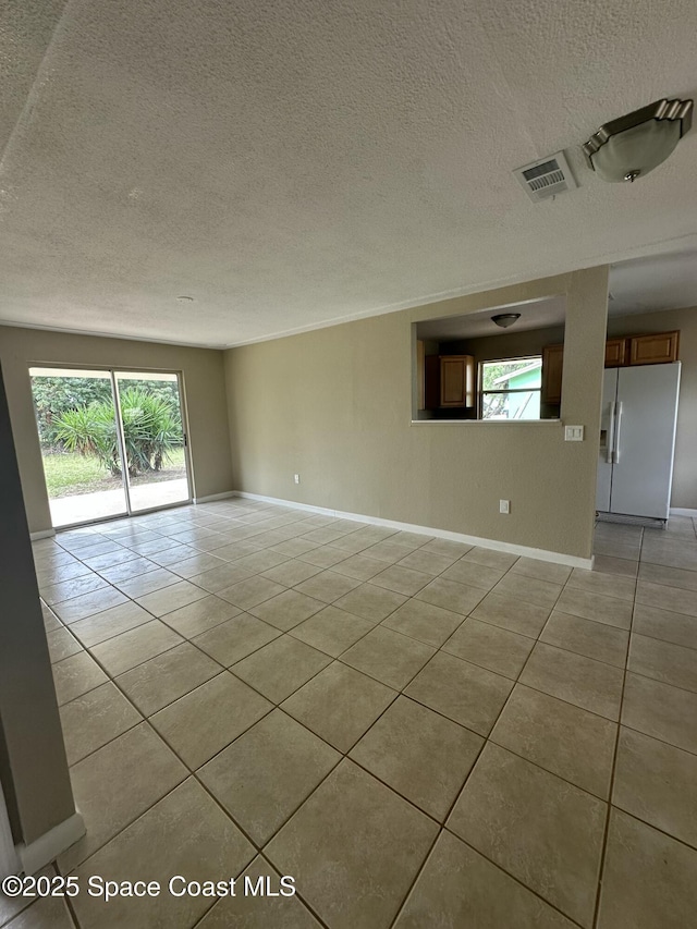 tiled empty room featuring a textured ceiling