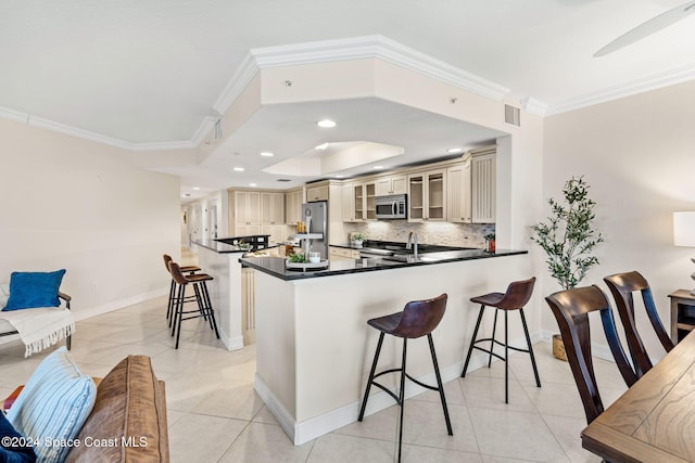 kitchen featuring kitchen peninsula, appliances with stainless steel finishes, crown molding, light tile patterned floors, and cream cabinetry