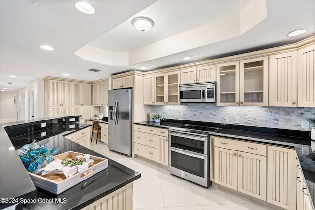 kitchen featuring decorative backsplash, stainless steel appliances, a tray ceiling, and light tile patterned flooring