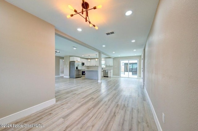 unfurnished living room featuring light hardwood / wood-style flooring and a chandelier