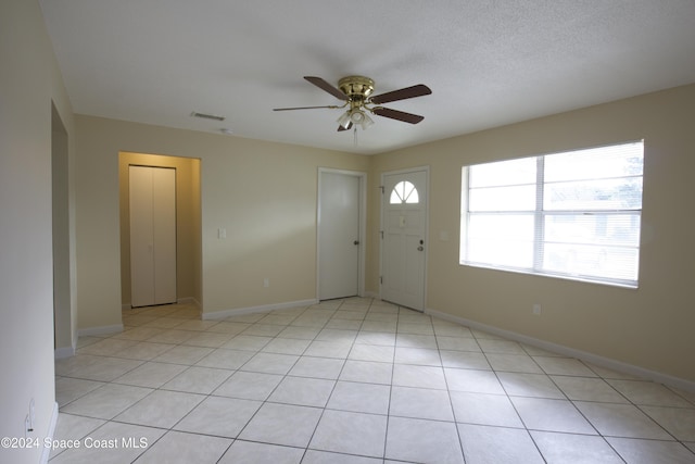 tiled entrance foyer featuring a textured ceiling and ceiling fan