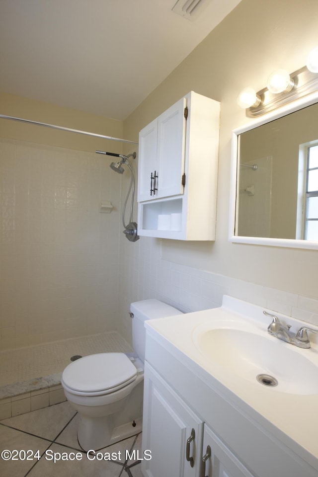 bathroom with tiled shower, tile patterned flooring, vanity, and toilet