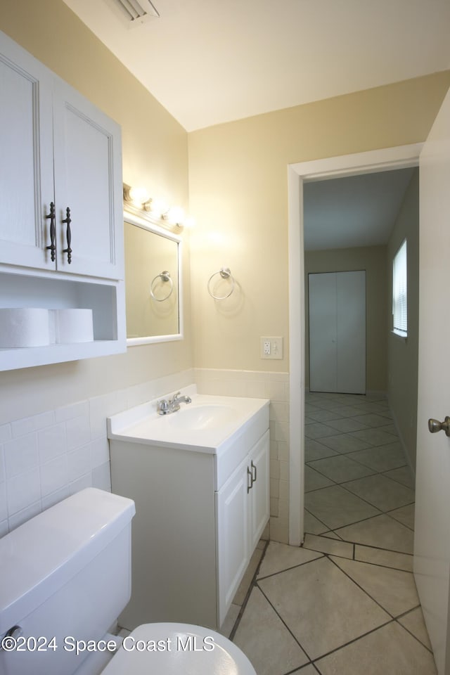 bathroom featuring tile patterned floors, vanity, toilet, and tile walls