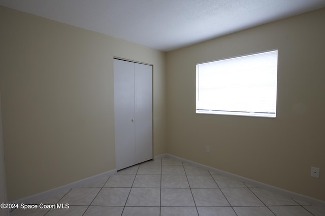 unfurnished bedroom with light tile patterned flooring and a closet