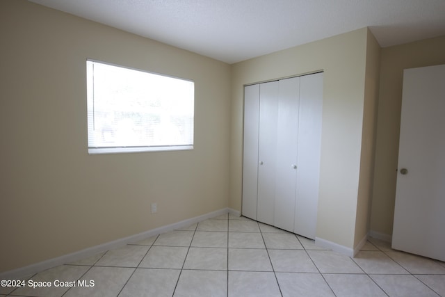 unfurnished bedroom with a closet and light tile patterned flooring