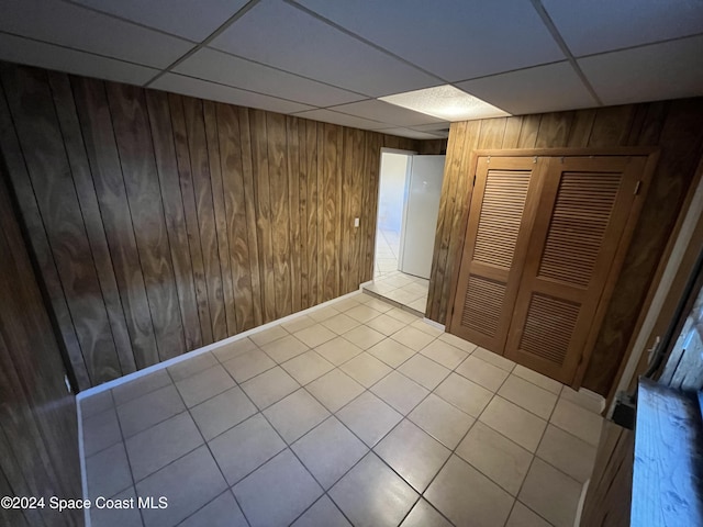 tiled spare room with a drop ceiling and wooden walls