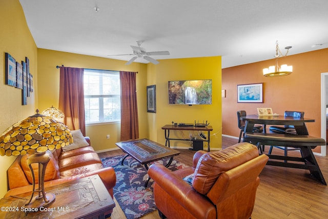 living room with ceiling fan with notable chandelier and light hardwood / wood-style floors