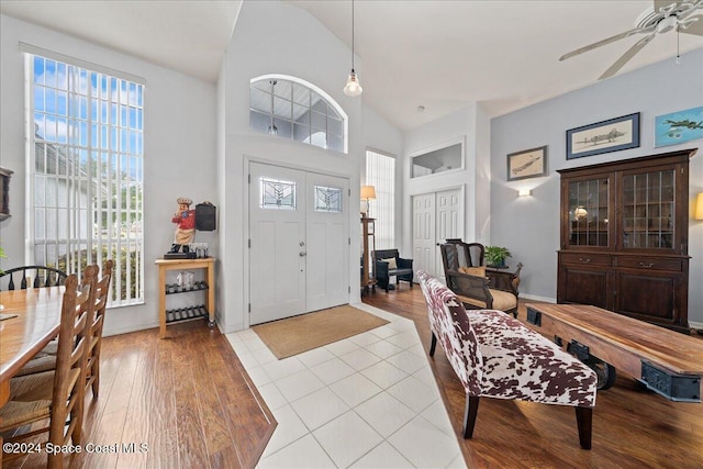 foyer featuring light tile patterned floors, high vaulted ceiling, and ceiling fan