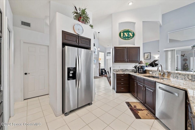 kitchen featuring light tile patterned flooring, dark brown cabinetry, stainless steel appliances, and sink