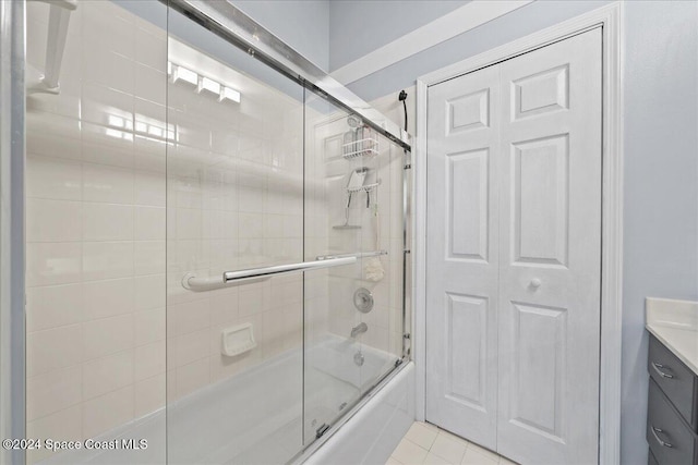 bathroom featuring tile patterned flooring, vanity, and enclosed tub / shower combo