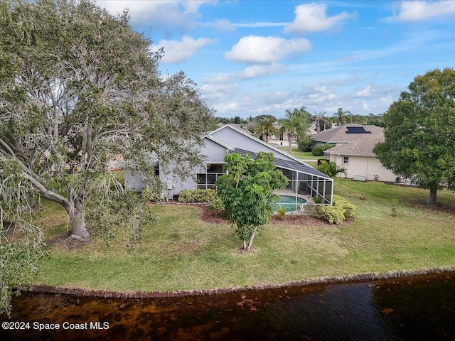 rear view of house featuring a lawn and a lanai