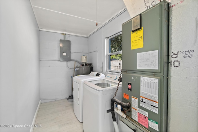 laundry room featuring water heater, separate washer and dryer, electric panel, and light hardwood / wood-style flooring