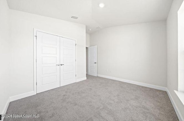 unfurnished bedroom featuring carpet flooring, a closet, and lofted ceiling