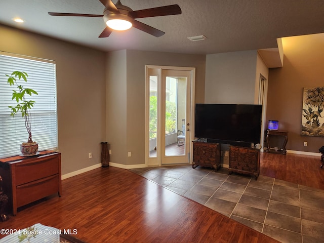 living room featuring ceiling fan, dark hardwood / wood-style flooring, and a textured ceiling