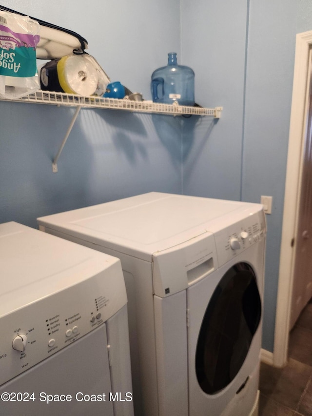 laundry area featuring washing machine and dryer and dark tile patterned floors