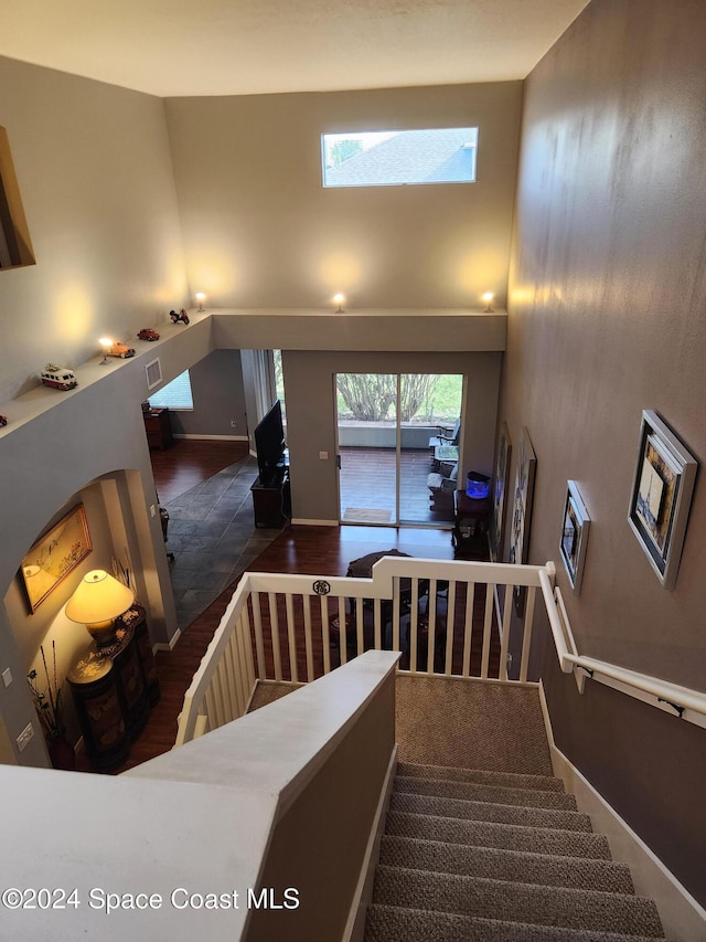 staircase featuring hardwood / wood-style floors, a skylight, and a high ceiling