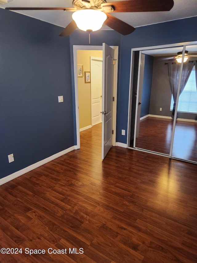 unfurnished bedroom featuring ceiling fan, dark wood-type flooring, and a closet