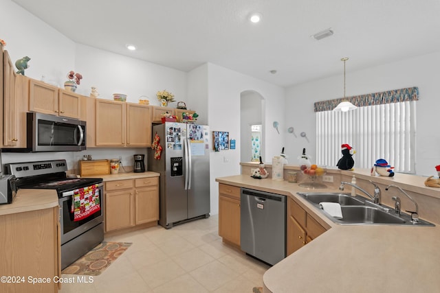 kitchen featuring appliances with stainless steel finishes, sink, light brown cabinets, hanging light fixtures, and plenty of natural light