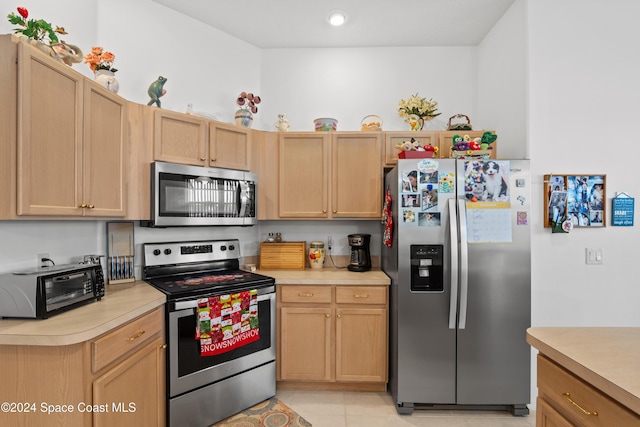 kitchen featuring light brown cabinets, light tile patterned floors, and appliances with stainless steel finishes