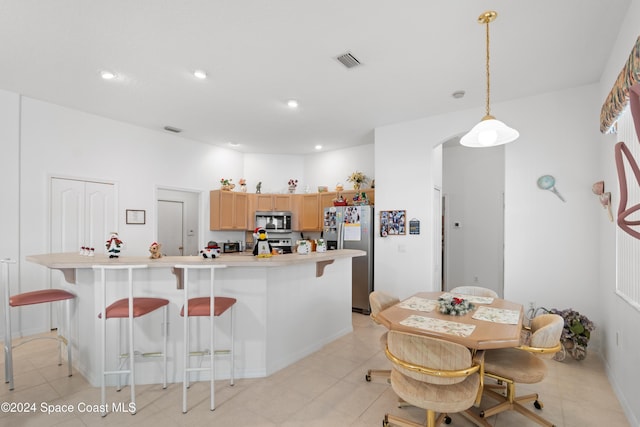 kitchen featuring a kitchen island with sink, hanging light fixtures, stainless steel appliances, and light brown cabinets