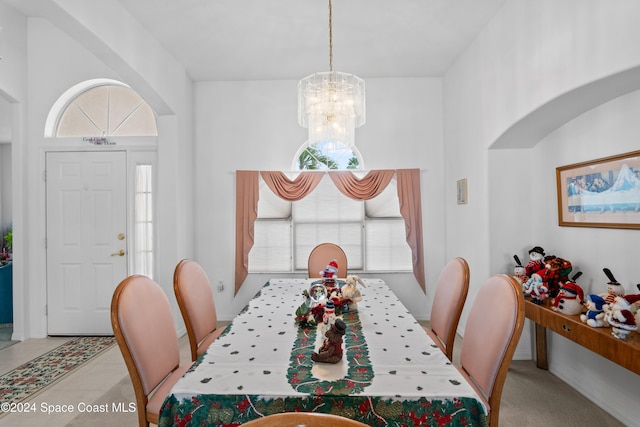 dining area featuring light tile patterned floors, a towering ceiling, and a notable chandelier