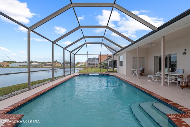 view of swimming pool featuring glass enclosure, ceiling fan, a water view, and a patio