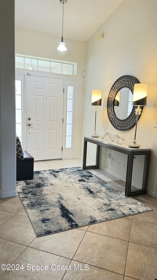 foyer with light tile patterned floors and vaulted ceiling