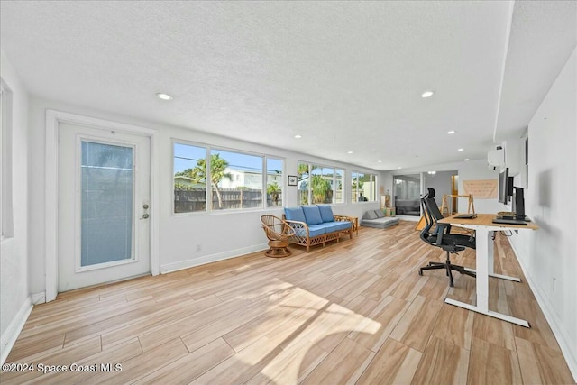 office area with light hardwood / wood-style floors and a textured ceiling