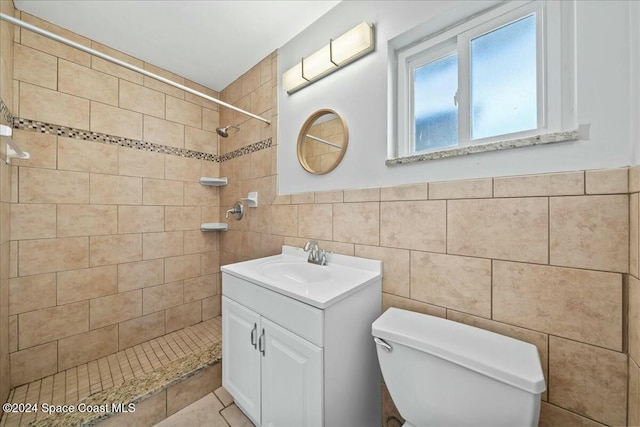 bathroom featuring toilet, vanity, tile walls, and tiled shower