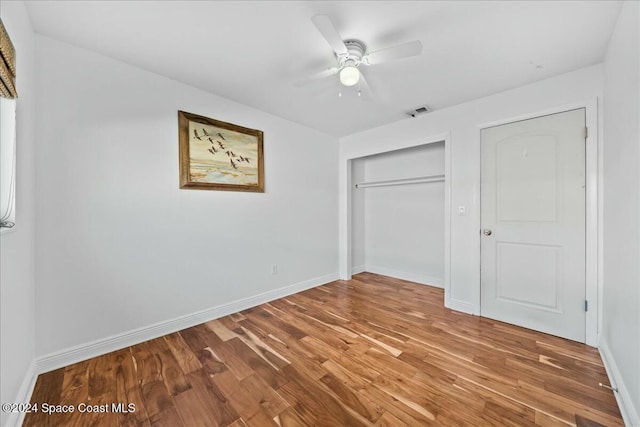 unfurnished bedroom with hardwood / wood-style flooring, ceiling fan, and a closet