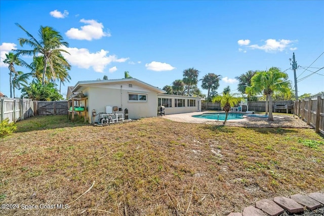 back of house featuring a fenced in pool and a lawn