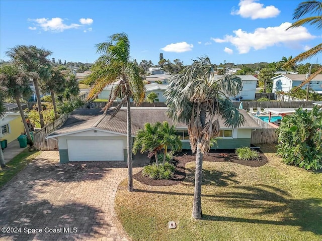 view of front of property with a fenced in pool, a front lawn, and a garage